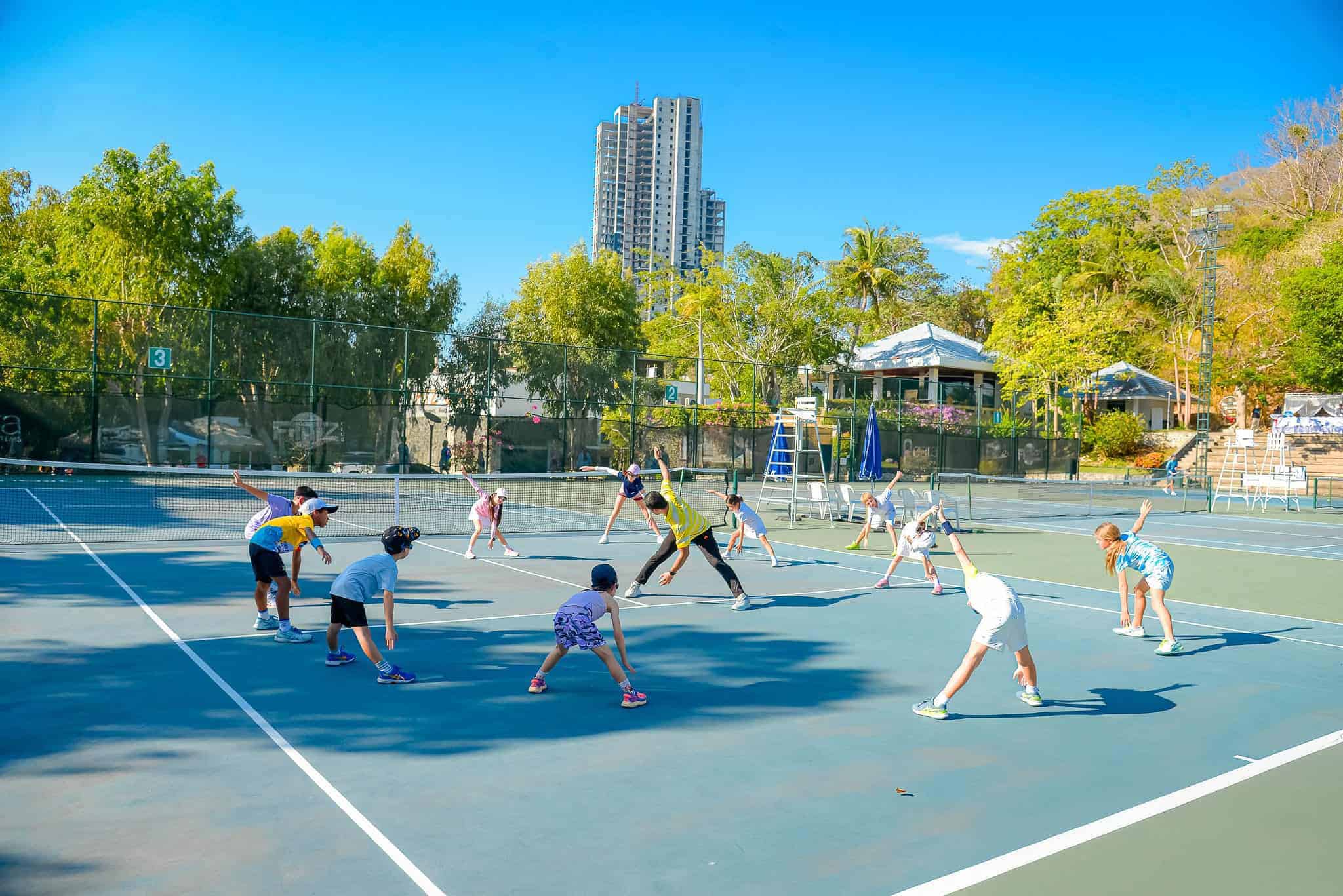 Tennis court at Royal Cliff Hotels Group with children practicing tennis outdoors.
